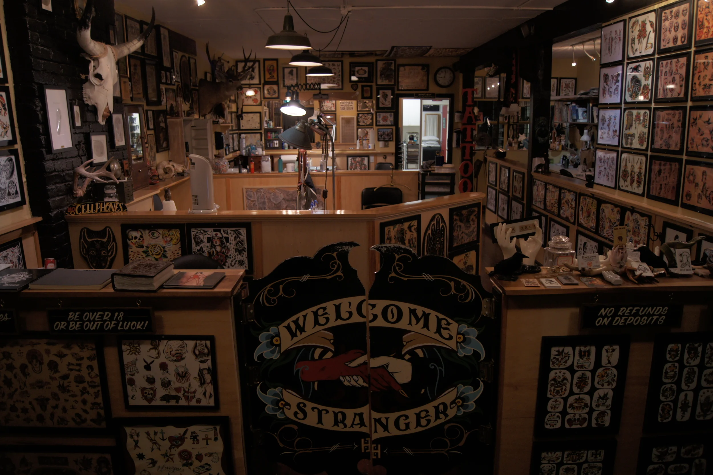 Idle Hand Tattoo interior -- Welcome Stranger gate, flash walls, dark atmosphere